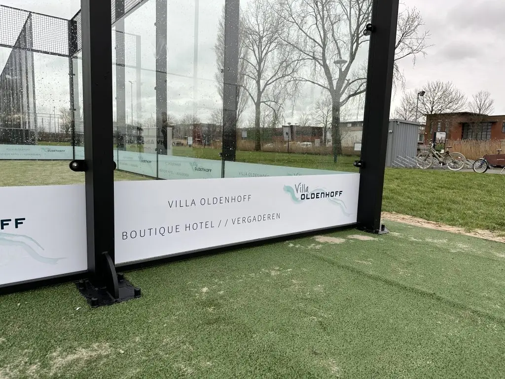 PadelReclame - Dubbelzijdige lage stickers op een padelbaan met sponsoring bij vereniging HV Abcoude.